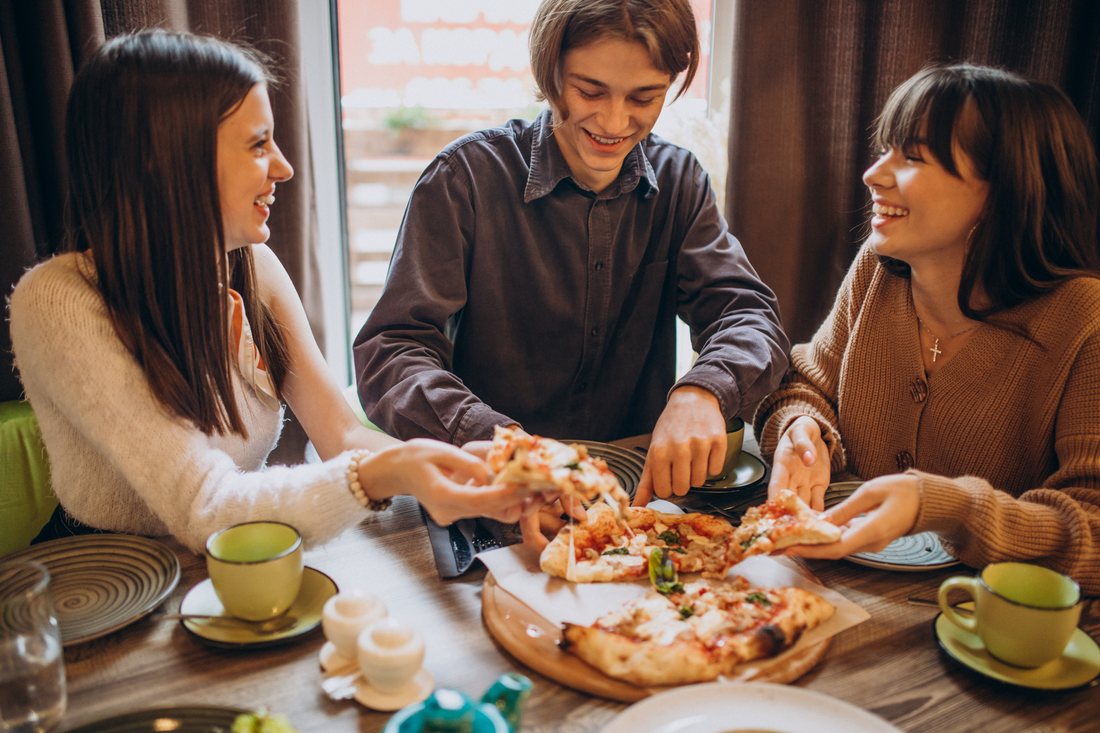 Troje przyjaciół dzieli się pizzą w kawiarni