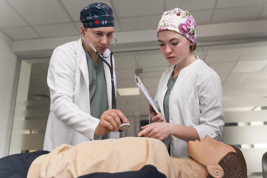 Studentka i student medycyny ćwiczą badanie na fantomie