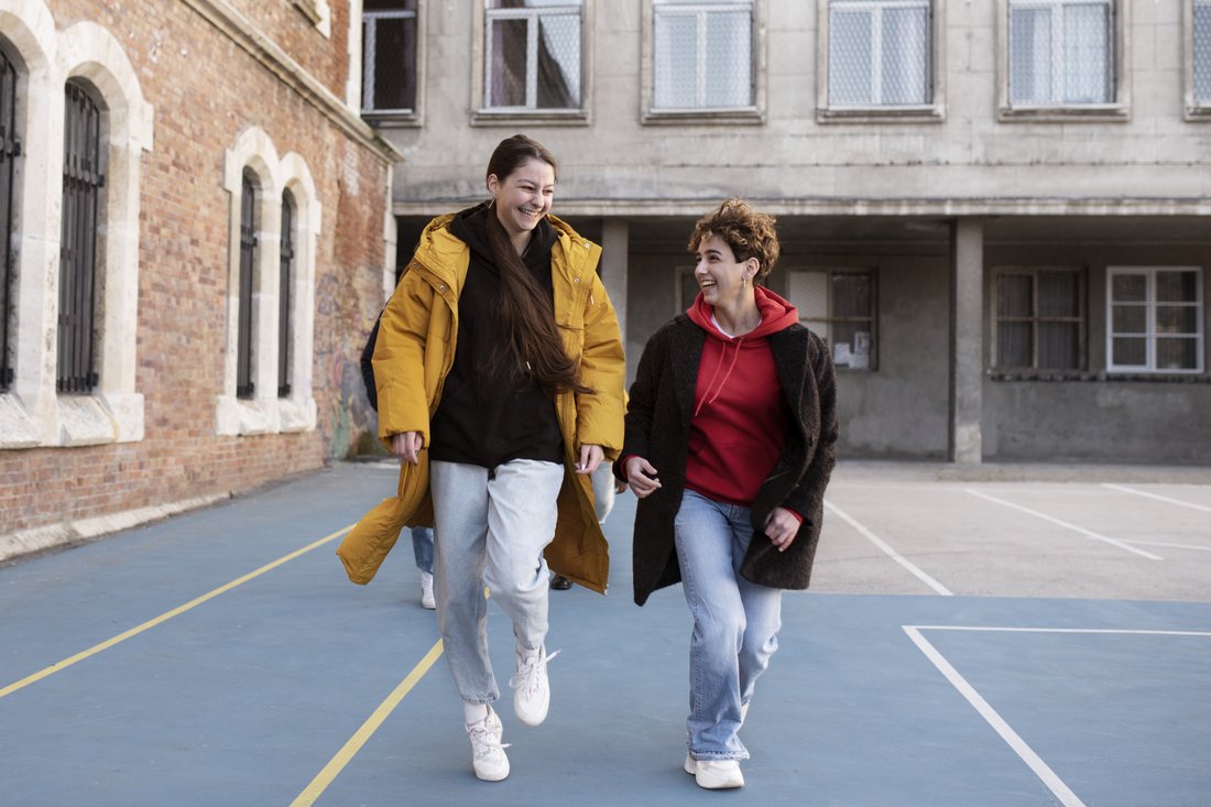 Dwie roześmiane studentki idą przed budynkiem uczelni